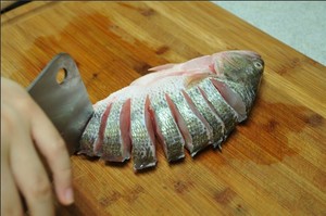 將鱸魚清洗干凈，從脊椎處切斷至腹部，腹部保留1cm左右不要切斷。