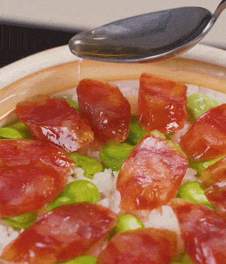 大米出現(xiàn)小孔時(shí)開蓋放香腸，往鍋邊淋入少許油，再燜煮8~10分鐘左右。