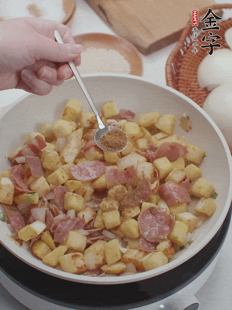 起鍋少油，煸香洋蔥丁、蔥白，加入金字培根火腿翻炒幾下，再加入饅頭丁、1小勺孜然粉、少許鹽翻炒均勻并鋪平。
